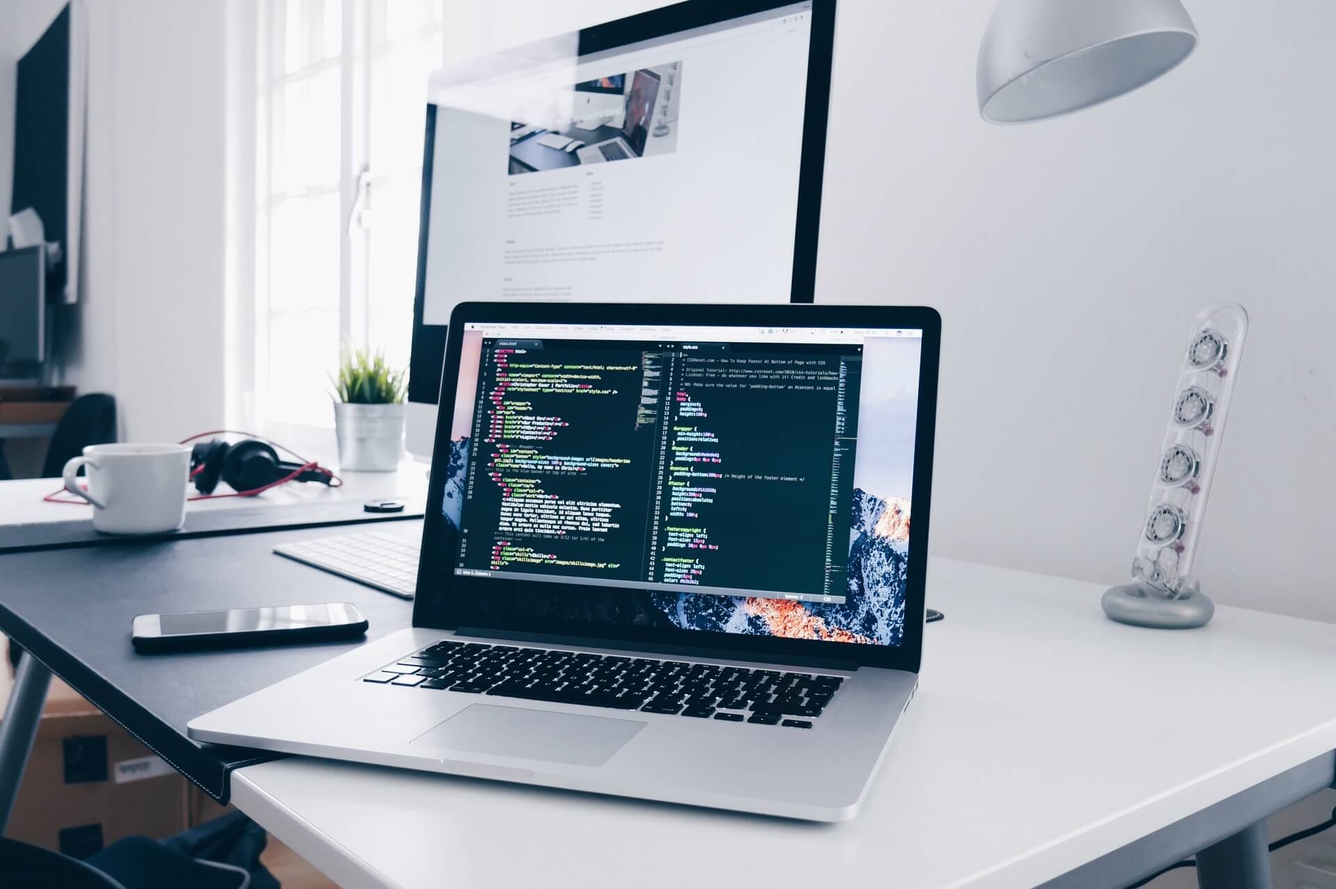 Table with white laptop and setup for coding.